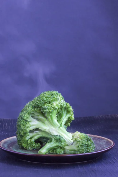 Brokoli kubis rebus di piring dengan latar belakang biru. Uap pada kubis — Stok Foto