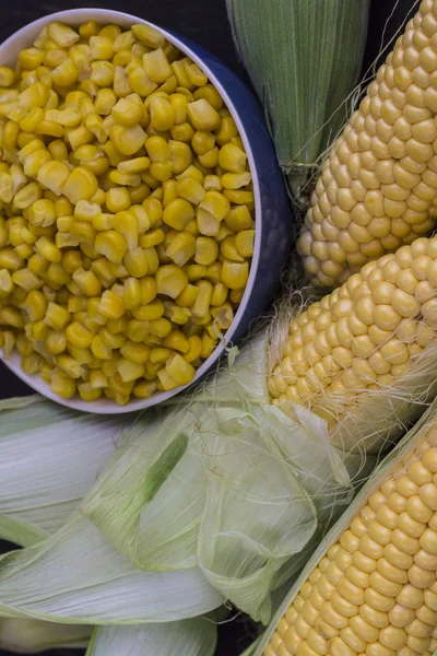 Maíz crudo en la mazorca y granos de maíz en un tazón azul —  Fotos de Stock