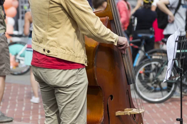 Street musician\'s hands playing double-bass in an urban environmt
