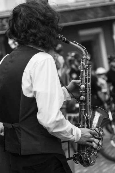 Street musician\'s hands playing saxophone in an urban environment. Black and white