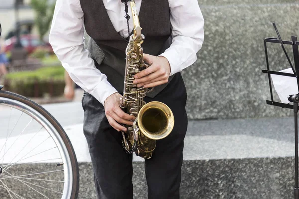 Manos de músico callejero tocando el saxofón en un entorno urbano — Foto de Stock