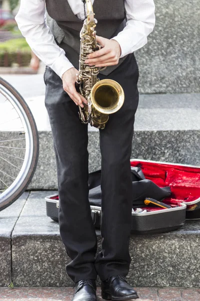 Manos de músico callejero tocando el saxofón en un entorno urbano — Foto de Stock