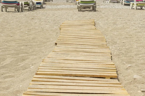 Praia de areia, pranchas de madeira, espreguiçadeiras à distância — Fotografia de Stock