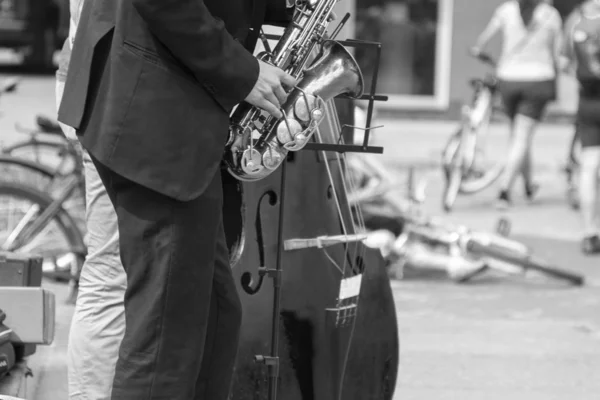 Manos de músico callejero tocando saxofón y contrabajo en un entorno urbano — Foto de Stock