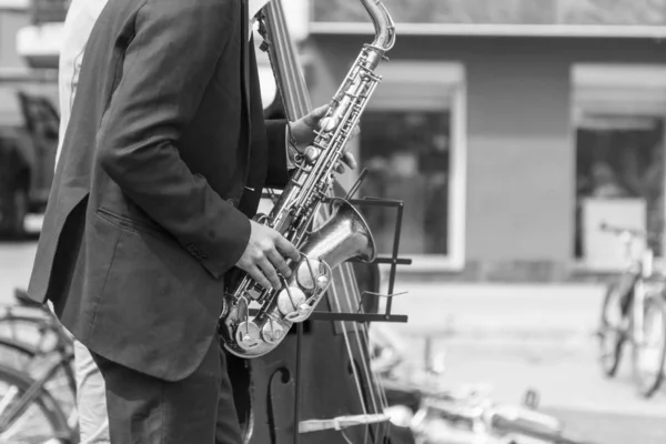 Manos de músico callejero tocando saxofón y contrabajo en un entorno urbano —  Fotos de Stock