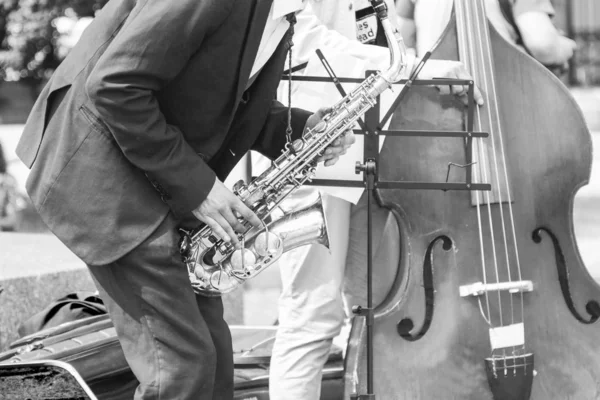 Street musician\'s hands playing saxophone and double-bass in an urban environment