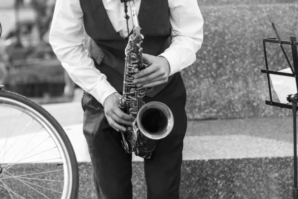 Street musician\'s hands playing saxophone in an urban environment. Black and white picture