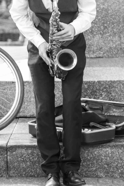 Street musician\'s hands playing saxophone in an urban environment