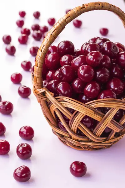 Cherry berries in a wicker basket. White background, part of the frame — Stock Photo, Image