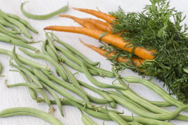 Beyaz bir arka plan üzerinde yeşil yaprakları ve fasulye ile Havuç