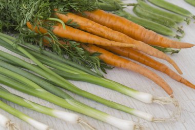 Beyaz bir arka plan üzerinde yeşil yaprakları, yeşil soğan ve fasulye ile Havuç