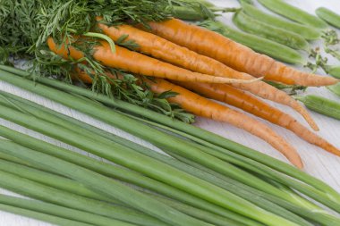 Beyaz bir arka plan üzerinde yeşil yaprakları, yeşil soğan ve fasulye ile Havuç