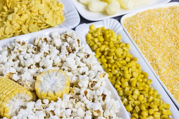 Un conjunto de productos hechos de maíz: palomitas de maíz, granos hervidos, cereales y granos de maíz. Placas blancas —  Fotos de Stock