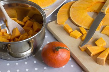 Kabak çorbası pişirme için hazırlık, bir tavada doğranmış kabak ve bir kesme tahtası üzerinde