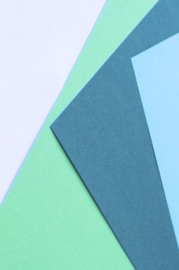 Bir üçgen şeklinde mavi, yeşil, turkuaz ve beyaz renklerde dört renkli kağıtlar. Arka plan, soyutlama