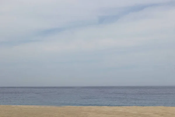 Přirozené pozadí: klidné moře, žlutý písek, modrá obloha — Stock fotografie