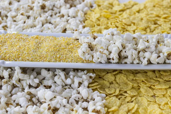 Corn products: cornflakes, corn grits and popcorn, close-up