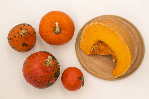 Ronde pompoenen op een witte achtergrond, een halve pompoen op een snijplank — Stockfoto