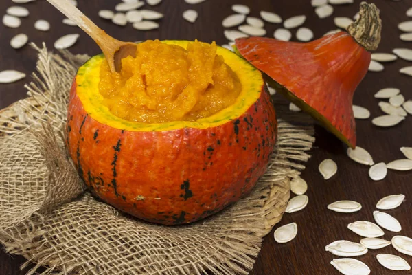 Pumpkin porridge in an orange pumpkin on burlap. Pumpkin seeds on he table ロイヤリティフリーのストック画像