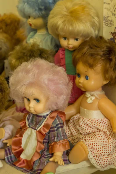Happy childhood concept: retro toys, dolls with multi-colored hair are sitting on the table