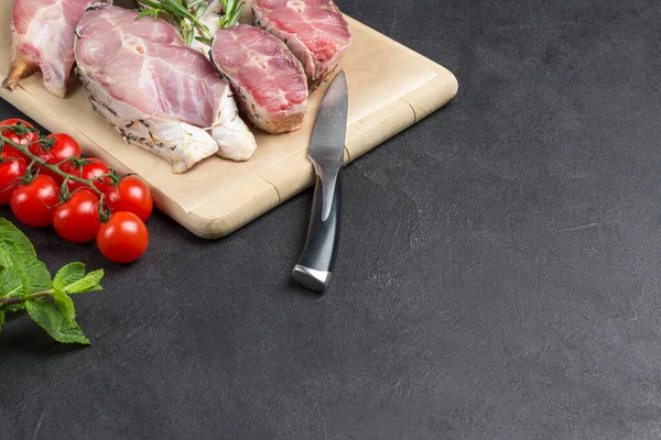 Kesme tahtasındaki taze nehir balığı. Masada bir dal vişneli domates. Siyah arka plan. Yukarıdan bak. Boşluğu kopyala