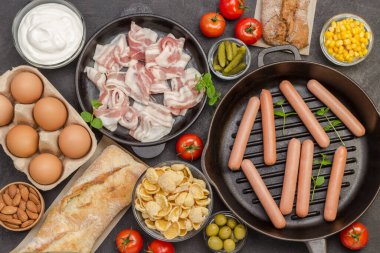 Tavada sosis. Pastırma peyniri, sebze, kurabiye mısır gevreği yoğurdu: Avrupa kahvaltısı için malzemeler. Siyah arka plan. Dengeli diyet yemekleri. Düz yatıyordu. 