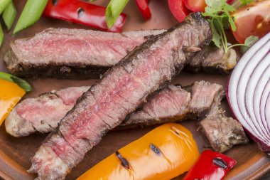 Sliced grilled marbled beef steak in plate with  Vegetables. Organic food. Close up.  Top view. Dark Wooden background