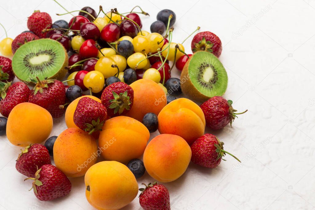 Assorted fresh berries and fruits. Apricots Kiwi Strawberry Cherry Blueberry on white background. Weight loss concept Top view. Copy space.