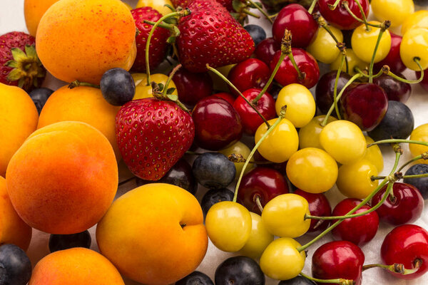 Mixture Apricots with yellow and red cherry, Blueberry Strawberry on white background. Weight loss concept Top view. 