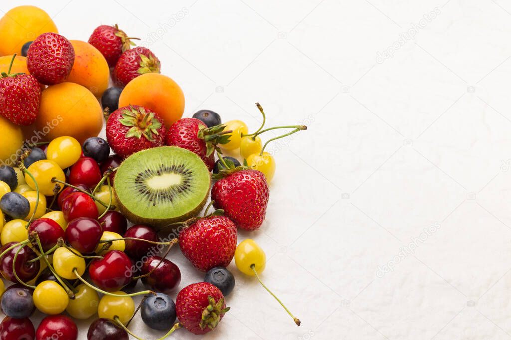 Assorted fresh berries and fruits. Apricots Kiwi Strawberry Cherry Blueberry on white background. Weight loss concept Top view. Copy space.