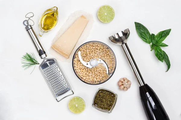 Pesto sauce. Cutter with pine nut, whisk, grater, pesto bowl, basil leaves, parmesan, garlic, lemon. Flat lay. White background