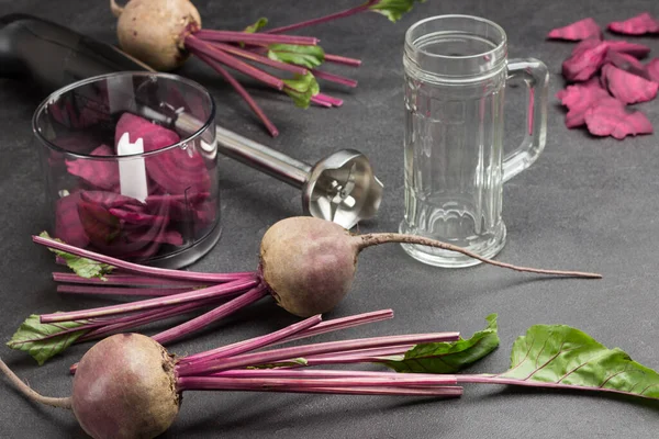 Beets with tops, sliced beets. Empty glass. Sliced beet in blender jar. Cutter. Top view. Black background — Stock Image Beets Tops Sliced Beets Empty Glass Sliced Beet Blender Jar Stock Picture