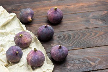 Kağıt üzerinde ve masada incir meyveleri. Koyu ahşap arka plan. Üst Manzara. Boşluğu kopyala