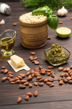 Ev yapımı pesto için malzemeler: fesleğen yaprağı, parmesan, çam fıstığı, sarımsak, yarım limon. Karanlık ahşap arka plan. Üst görünüm