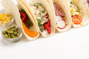 Vejetaryen salatasıyla sarılmış vejetaryen tortilla. Cam kaselerde konserve mısır ve bezelye. Beyaz arka plan. Üst Manzara. Boşluğu kopyala