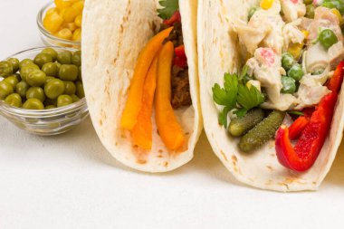 Vejetaryen salatasıyla sarılmış vejetaryen tortilla. Cam kaselerde konserve yeşil bezelyeler. Beyaz arka plan. Üst Manzara. Kapat.