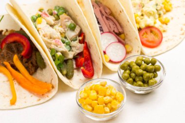 Cam kaselerde konserve mısır. Vejetaryen salatasıyla sarılmış vejetaryen tortilla. Beyaz arka plan. Seçici odak