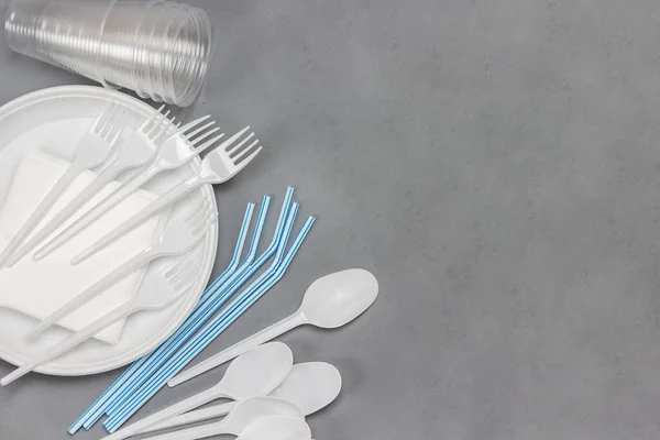 Tek kullanımlık plastik sofra takımı. Tabak, kaşık, çatal, pipet. Plastik işleme sorunu. Ekoloji çevresel bakım. Düz yatıyordu. Gri arka plan. Boşluğu kopyala