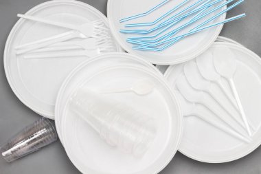 Tek kullanımlık plastik sofra takımı. Tabak, kaşık, çatal, pipet. Plastik işleme sorunu. Ekoloji çevresel bakım. Düz yatıyordu. Gri arkaplan