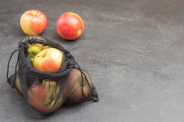 Apples in black reusable bag. Apples on table. Ecological concept. Black background. Top view. Copy space