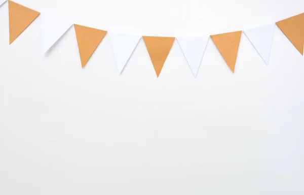 Hanging paper flags on white wall background, decor items for party, festival, celebrate event