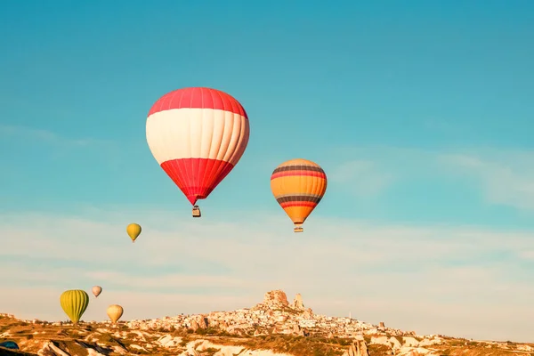 日出时在土耳其卡帕多西亚 Uchisar 城堡附近飞行的五颜六色的热气球 — 图库照片