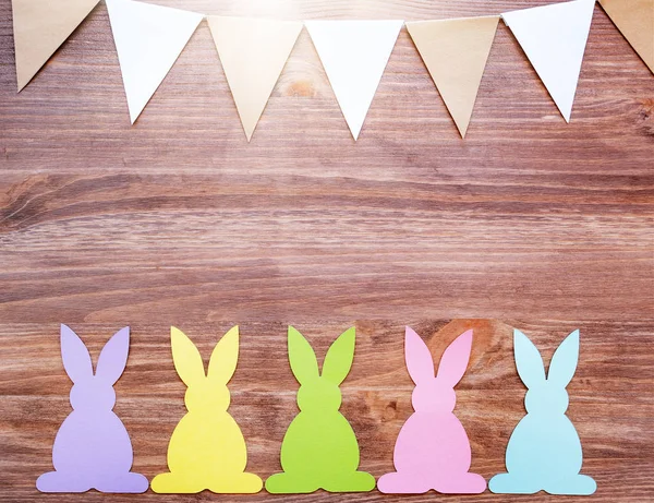 Easter card with rabbits and garland flags on wooden background — Stock Photo, Image