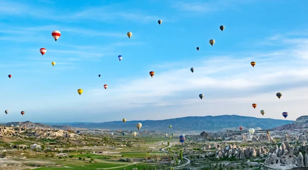 Kleurrijke hete lucht ballonnen vliegen over rock landschap in Cappadocië — Stockfoto