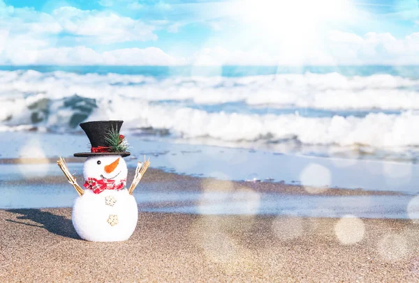 Boneco de neve sorridente na praia ensolarada. Conceito de férias para cartões Feliz Natal e Feliz Ano Novo — Fotografia de Stock