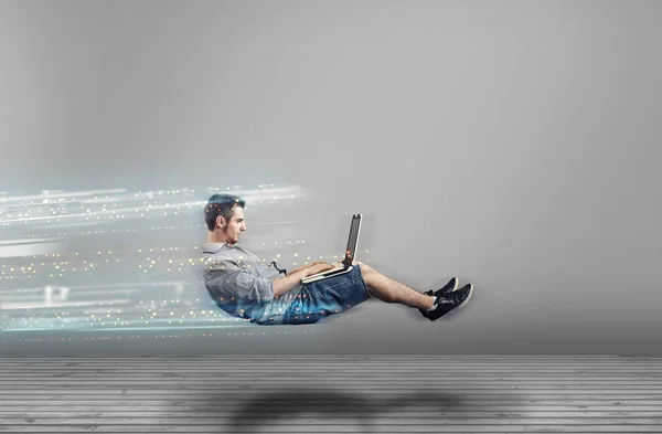 Adam bir dizüstü bilgisayar kullanarak bir beyaz odada levitating hızlı. Yüksek hızlı tarama.