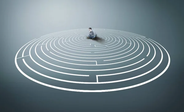 Thoughtful man sitting in the middle of a round maze.