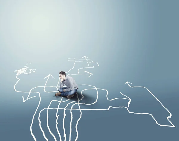 Farklı okları yere çizilmiş üzerinde oturan karışık adam. Zor seçimler kavramı.