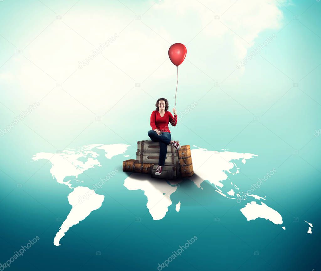 Happy woman holds a red balloon sitting on luggages on world map.