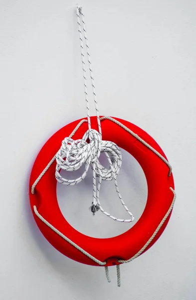 Cankurtaranlar kırmızı kurtarma halkası şamandırası havuzda beyaz duvara asılı. Beyaz duvarda bir tahta ile Beyaz Yaşam şamandırası. Beyaz duvarda asılı kırmızı cankurtaran şamandırası. Kırmızı, daire, yaşam, kurtarma, yüzük, şamandıra.